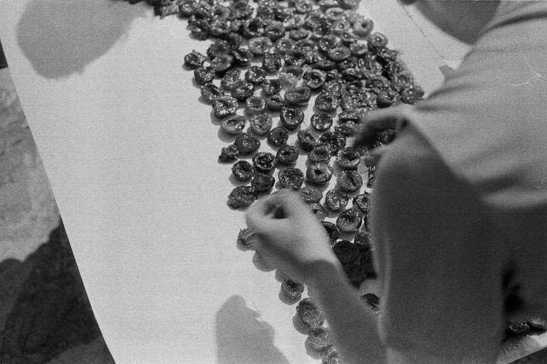 Hands arranging small food pieces on a table in a black-and-white photograph