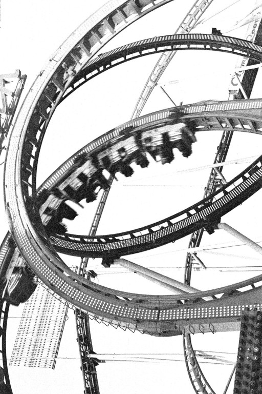 Roller coaster twisting through a loop in a black-and-white photograph